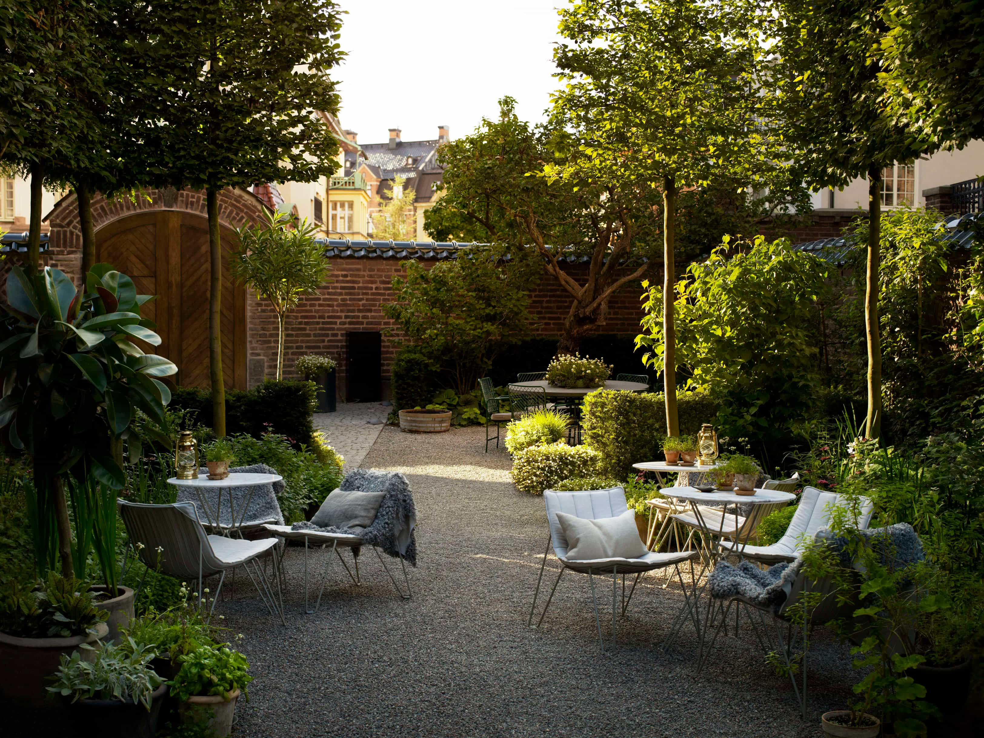 table and chairs on gravel surrounded by a walled in garden courtyard during day