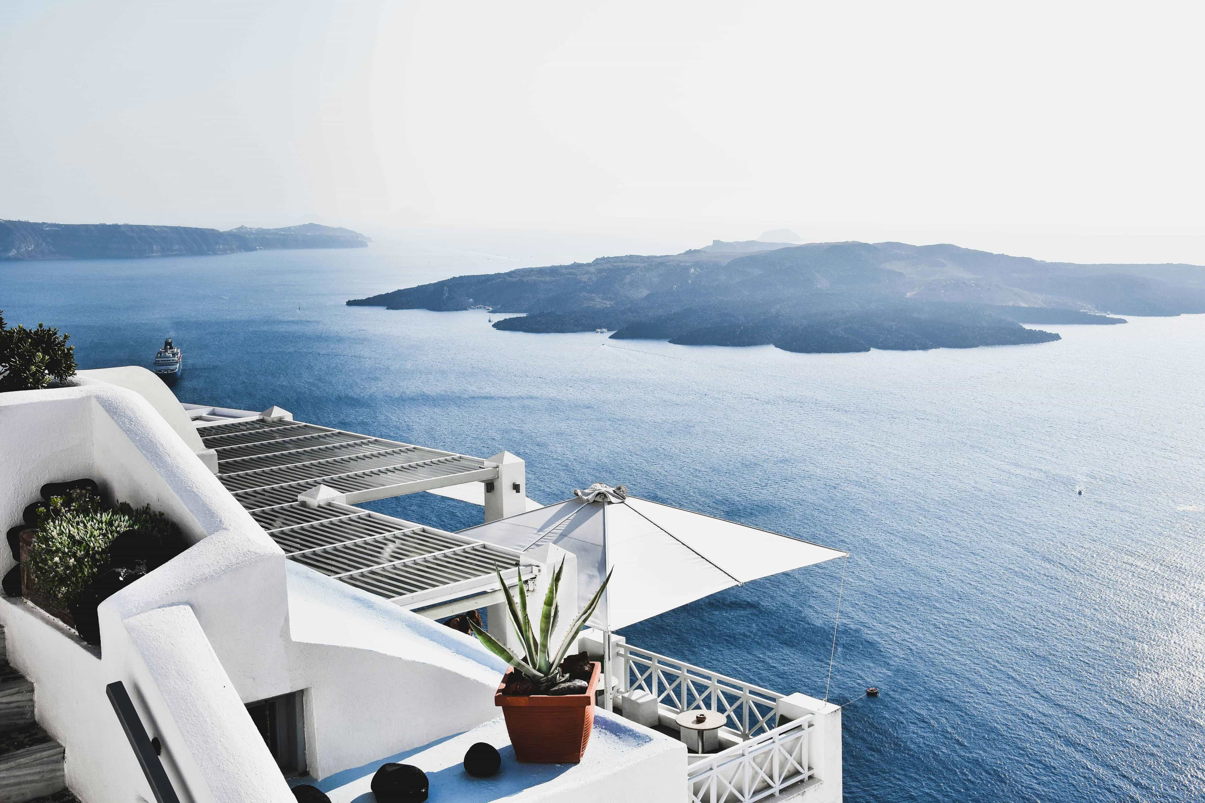 Whitewashed terrace with sea views overlooking a blue caldera and island in Santorini, Greece