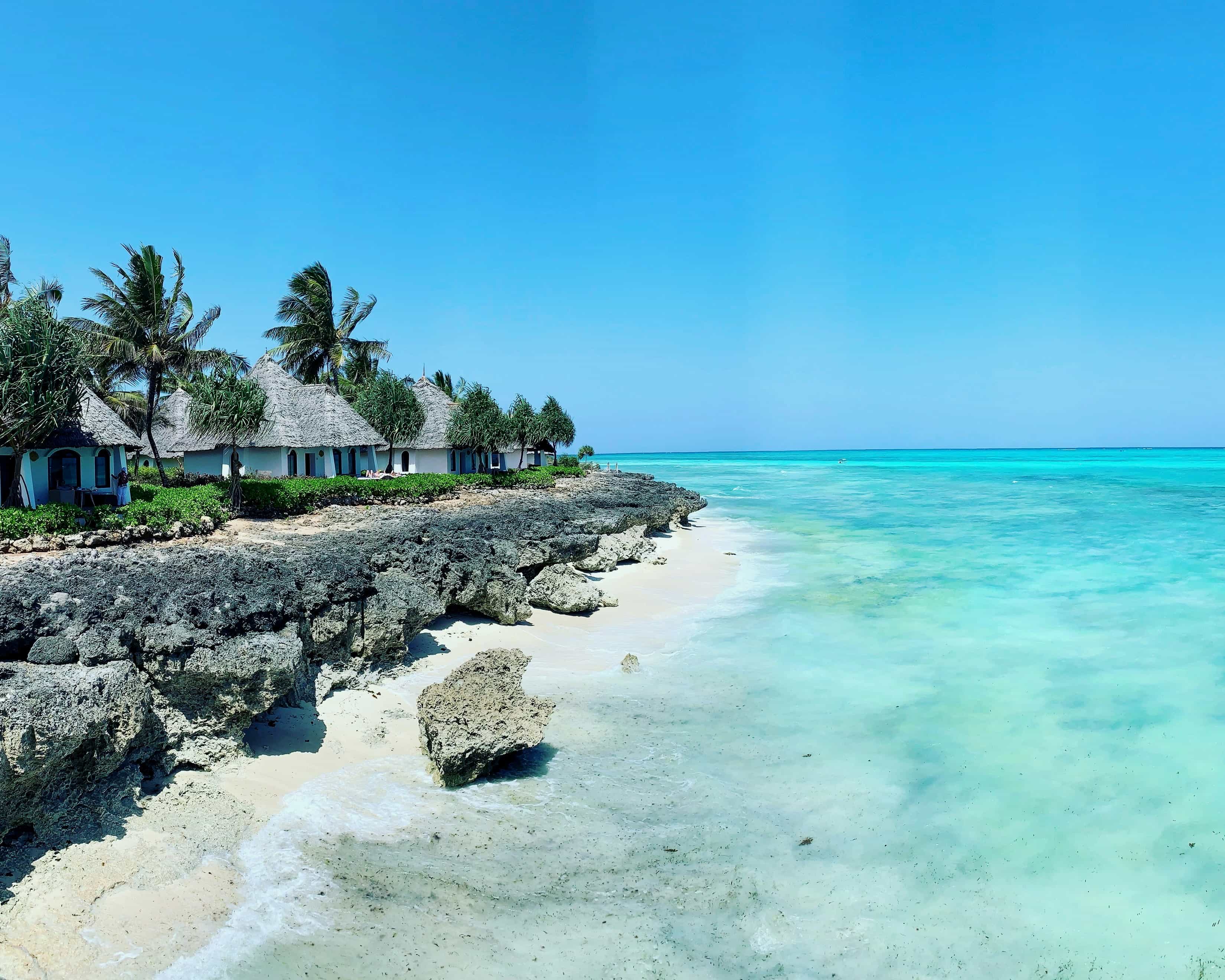 resort villas on a rocky bluff beside turquoise ocean during day