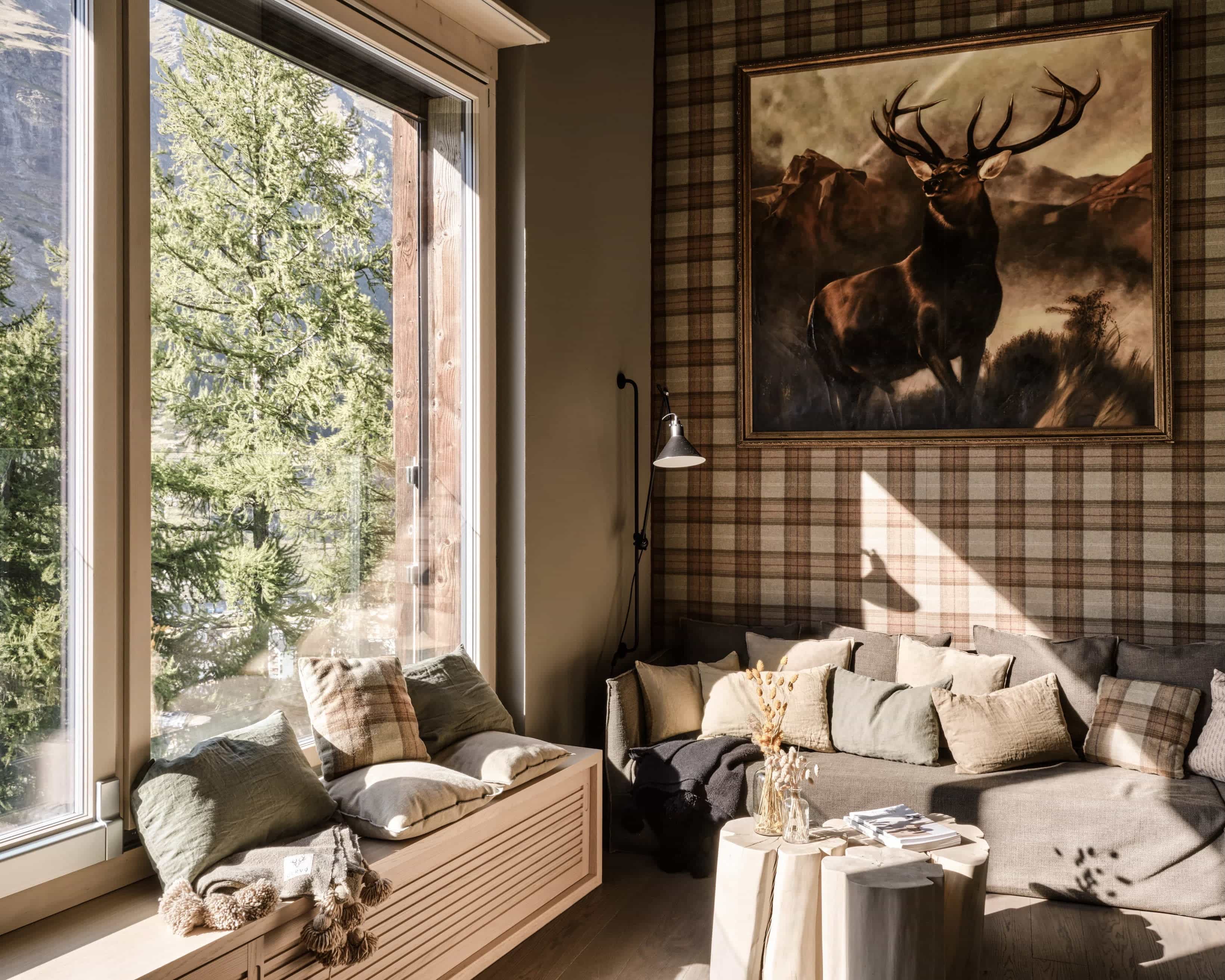 cozy living room with plaid wallpaper, deer wall art, and trees outside