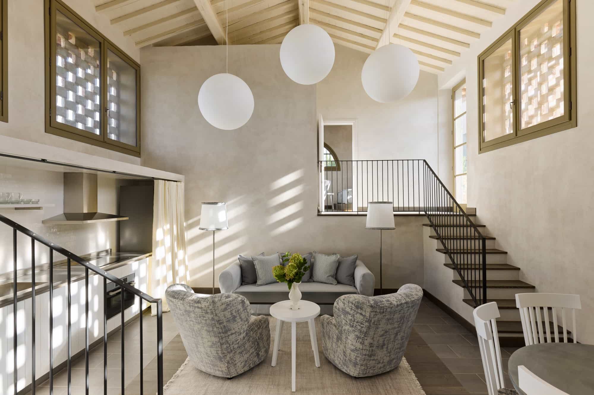 a fancy living room with pale furniture and spherical light fixtures