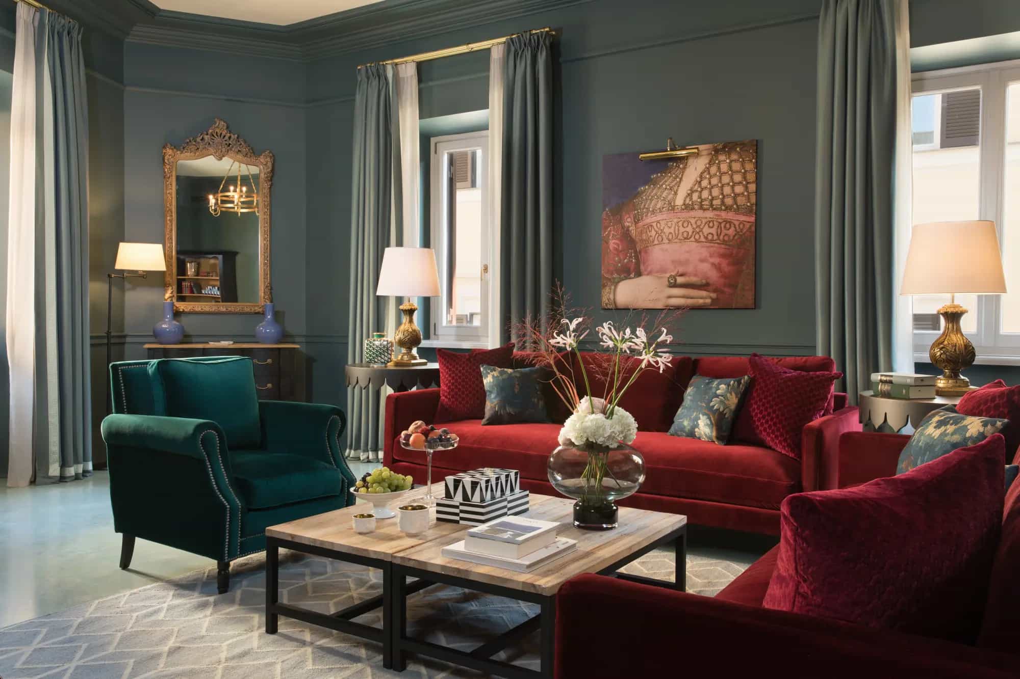 a stately living room with blue walls and red velvet couches