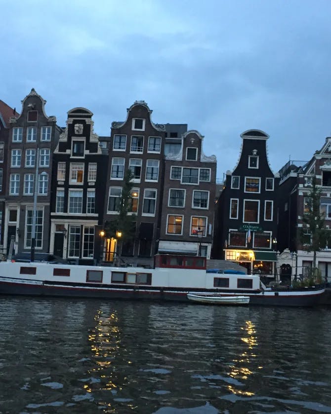 Picture of Iconic Dancing Houses in Amsterdam at dusk with a boat on the river
