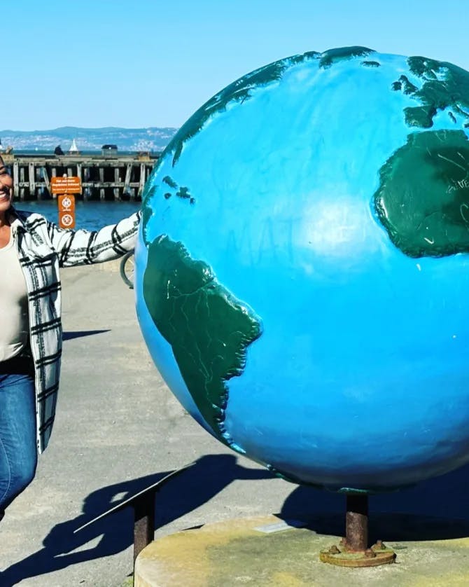 Travel advisor Joanna Alejandro leans against a statue of the earth