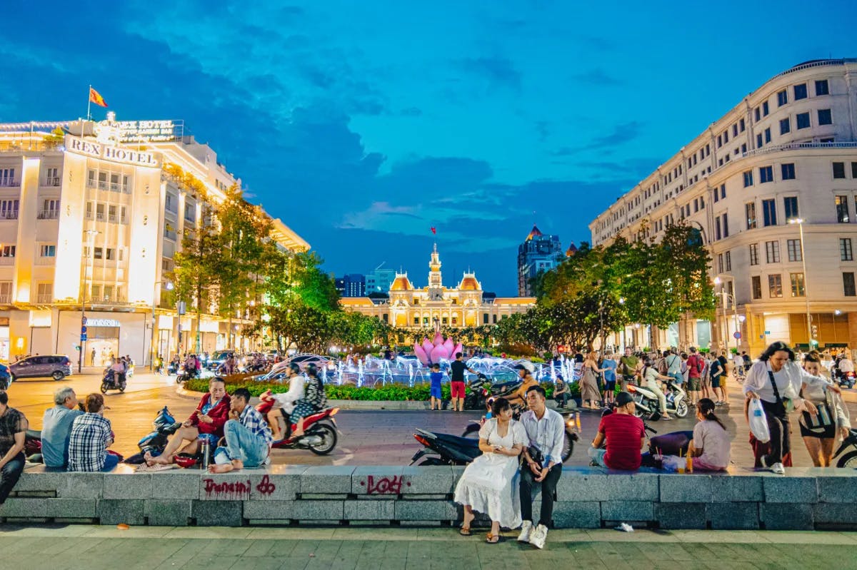 People sitting in front of buildings and a fountain.