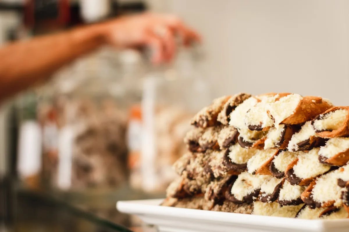 A stack of cream-filled cannolis with candy jars in the background