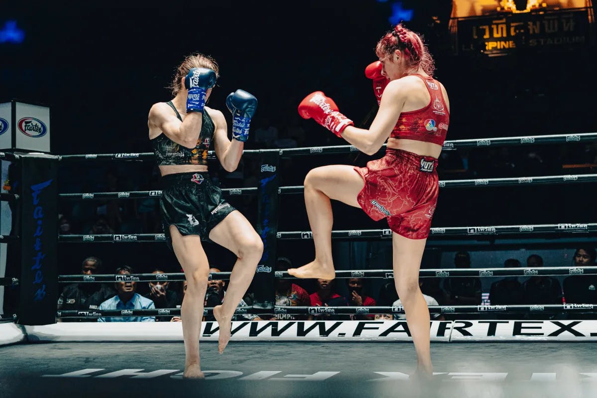 Two women practicing Muay Thai in a ring in Bangkok with an audience