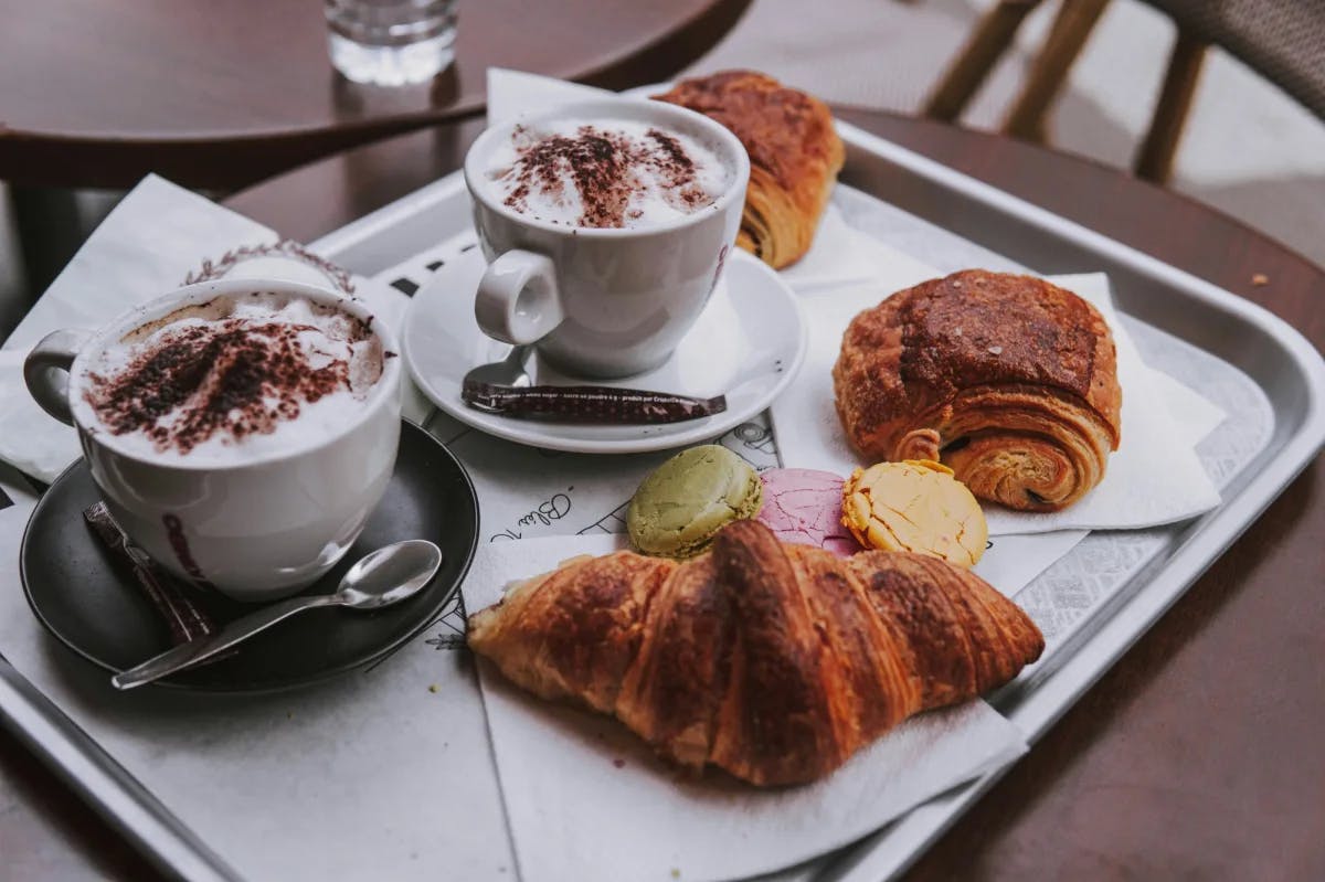 Two croissants with two coffees on a tray.