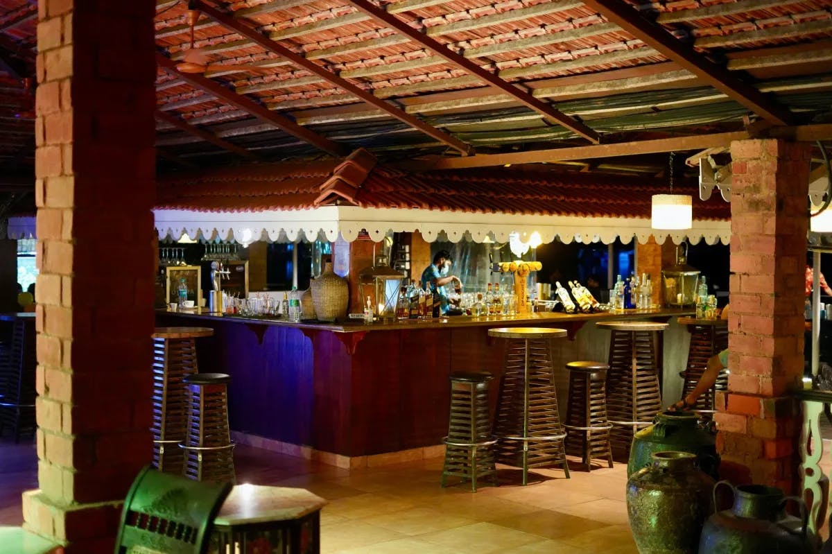 A brown wooden bar stools and table at a  drinks lounge in a resort.