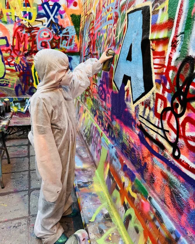 A child adding his own art to a graffiti wall. 