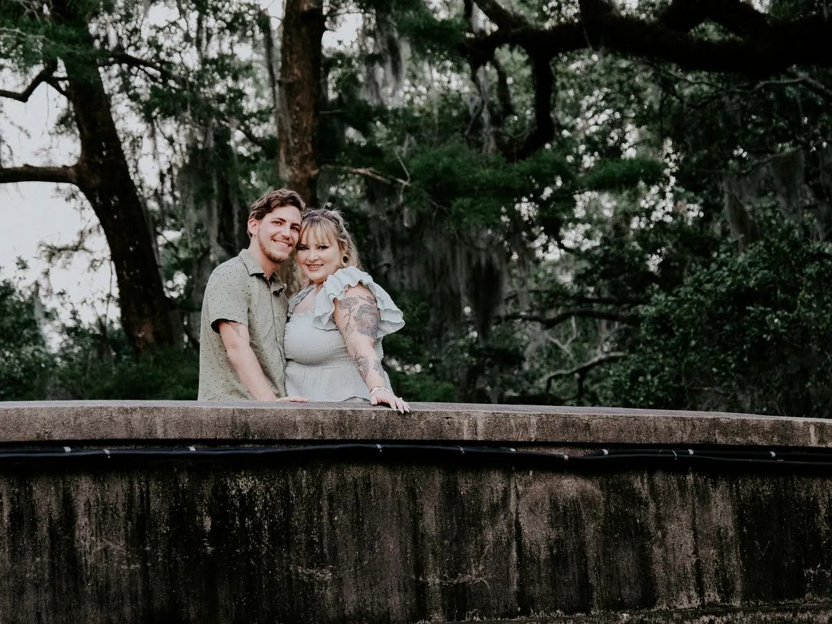 A couple posing on a bridge during the daytime.