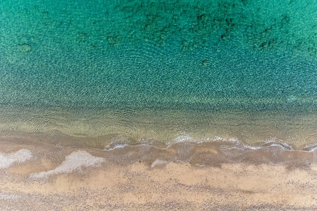 An aerial view of the green-colored water near the shore during the daytime.