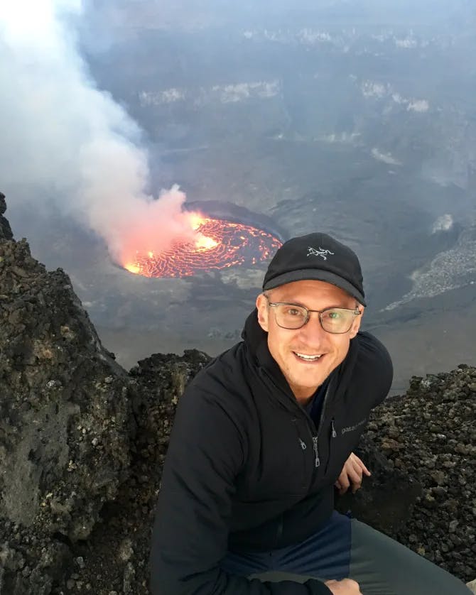 Michael on a posing on a ledge with the inside of an active volcano below him.