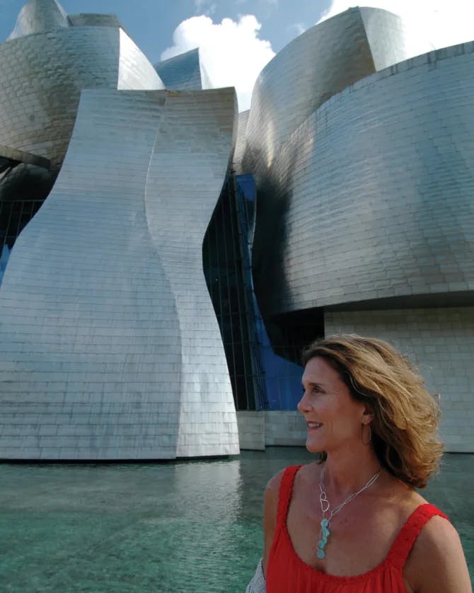 Melanie in a red dress with huge concrete architecture in background