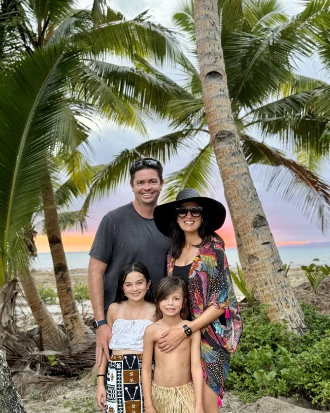 Nadiah and her family posing with lush greenery and palm trees. 
