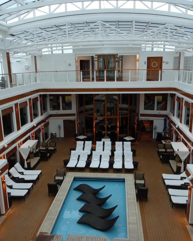 indoor pool deck surrounded by balconies and pool chairs