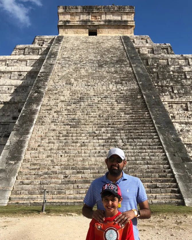 A man and a child posing in front of a pyramid.