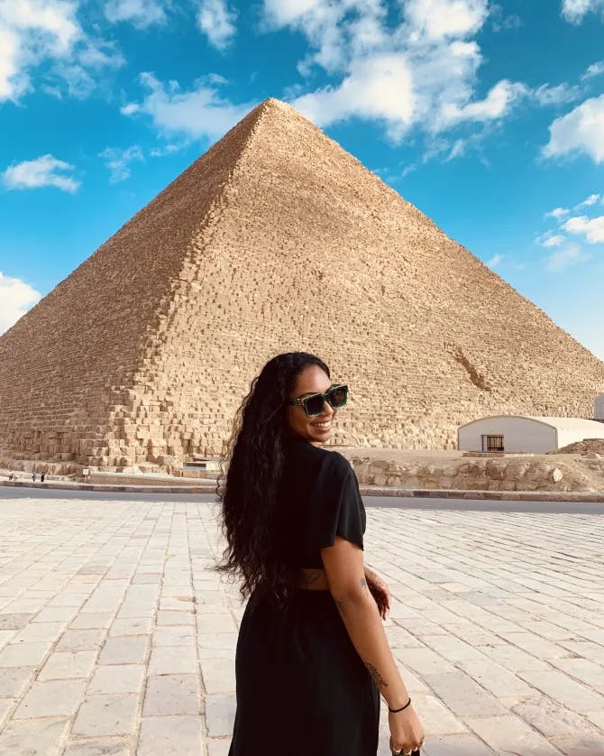 Travel advisor stands in front of pyramid wearing a black dress