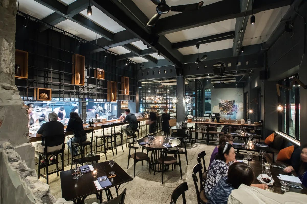 The interior of the modern 80/20 restaurant in Bangkok with dark beams and an open kitchen