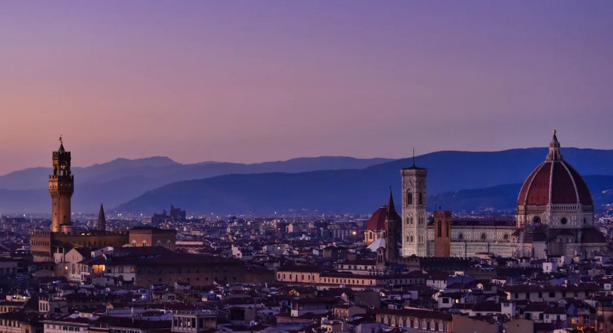 A view of the Florence city scape with a purple tinted sunset in the background.