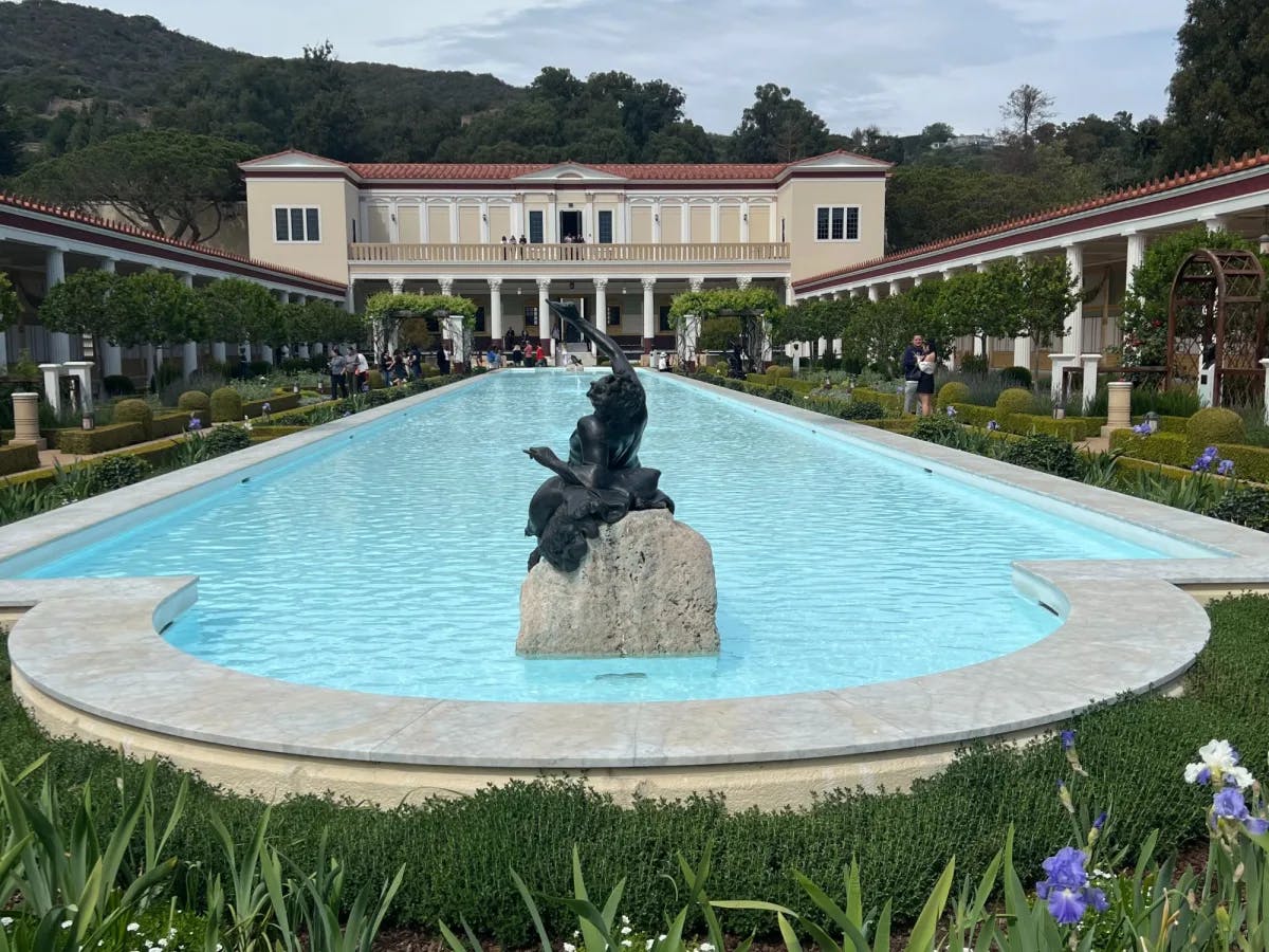 A villa with a big pool with statue in front. 