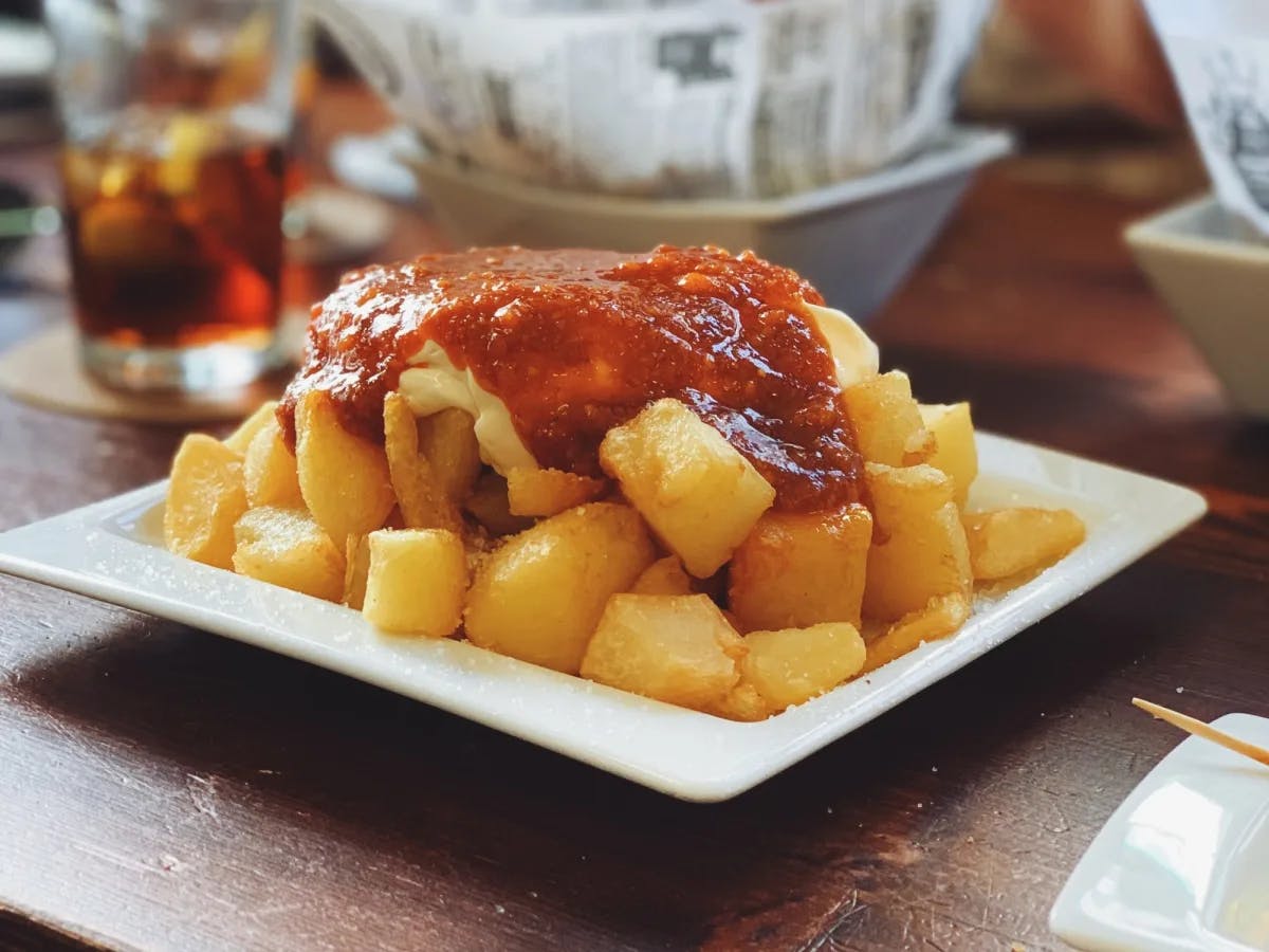 Fried potato cubes with ketchup on a white plate. 