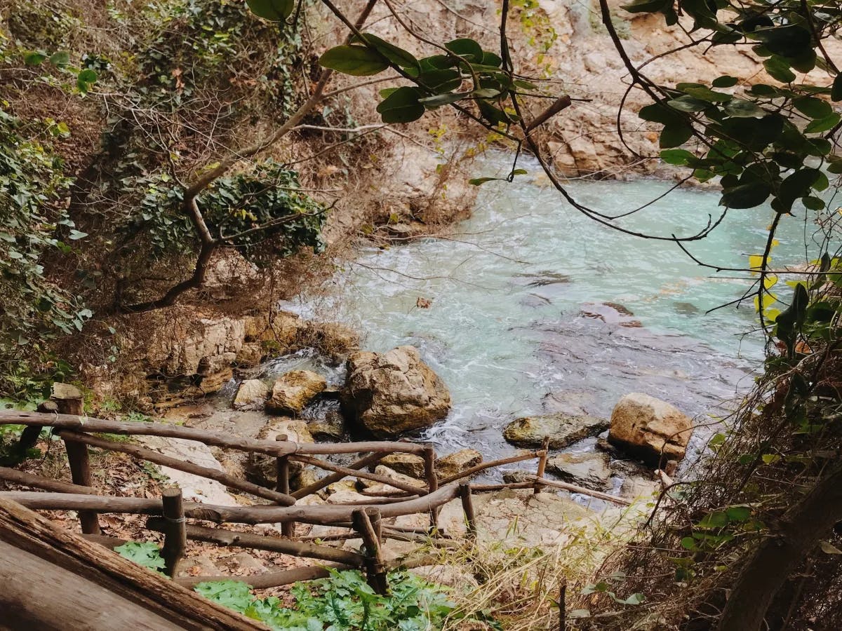 A view of a wooden staircase leading down to a body of water and rocks in the surrounding areas.