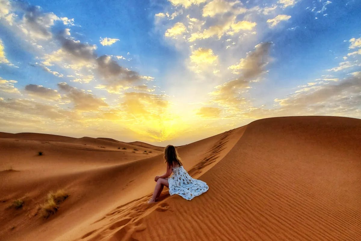 girl-sitting-on-sand-dune-morocco-travel-guide