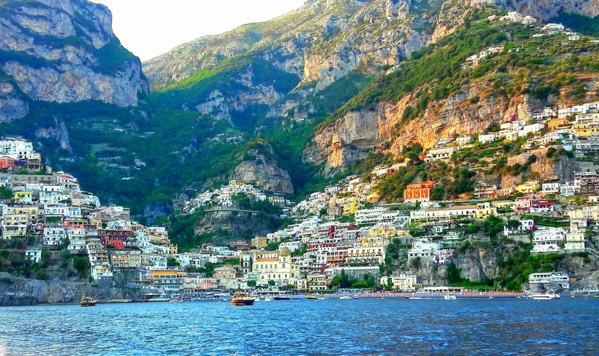 A view from the sea of the Positano coastline with picturesque colorful buildings built into the cliff