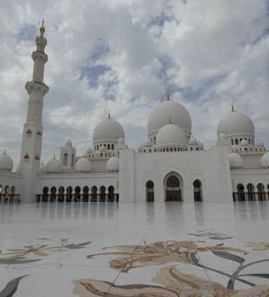 Beautiful view of the grand white buildings of Sheikh Zayed Grand Mosque and its white shiny courtyard