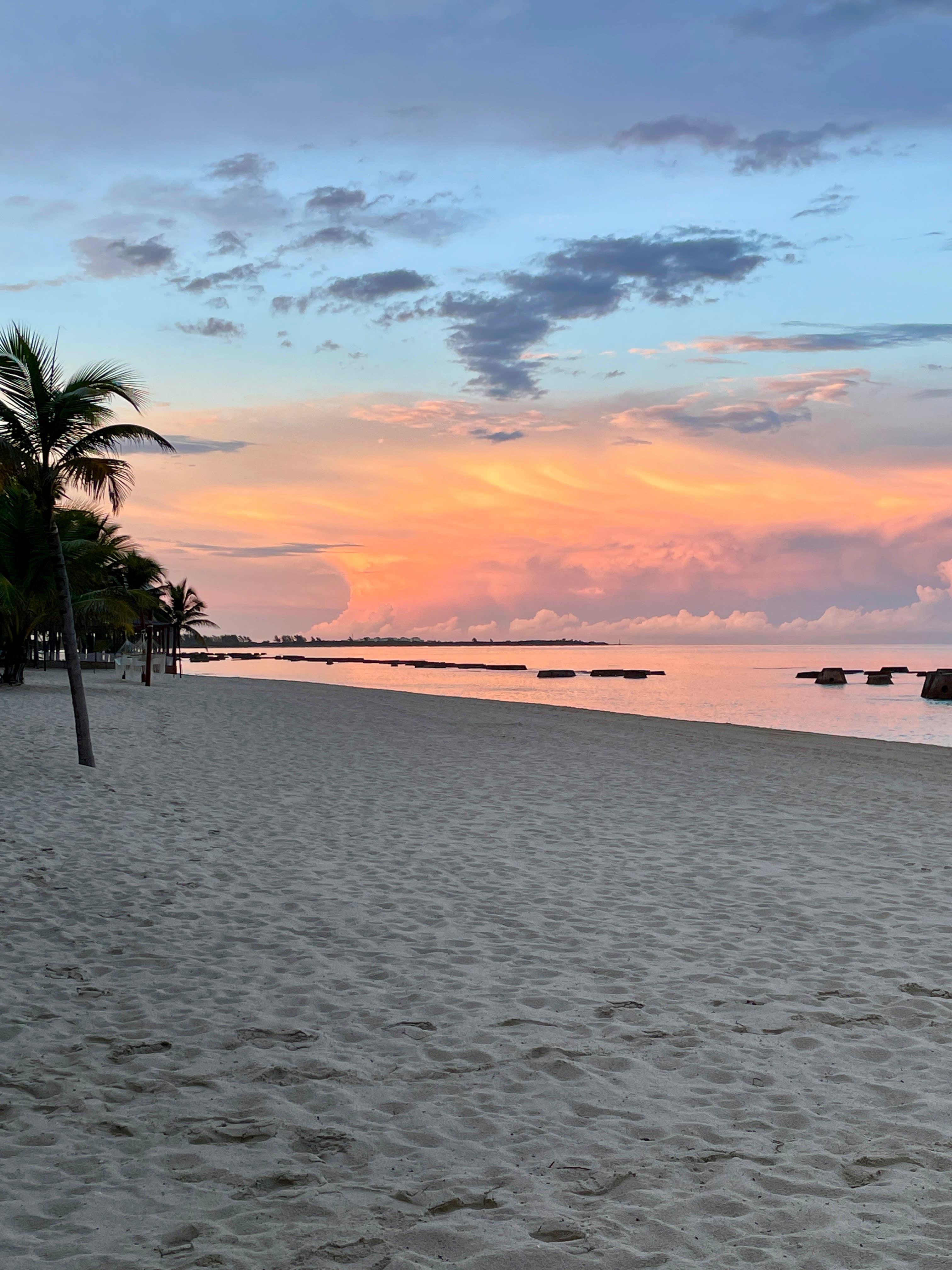 View of a pastel colored sunset over the ocean and a clean, empty beach