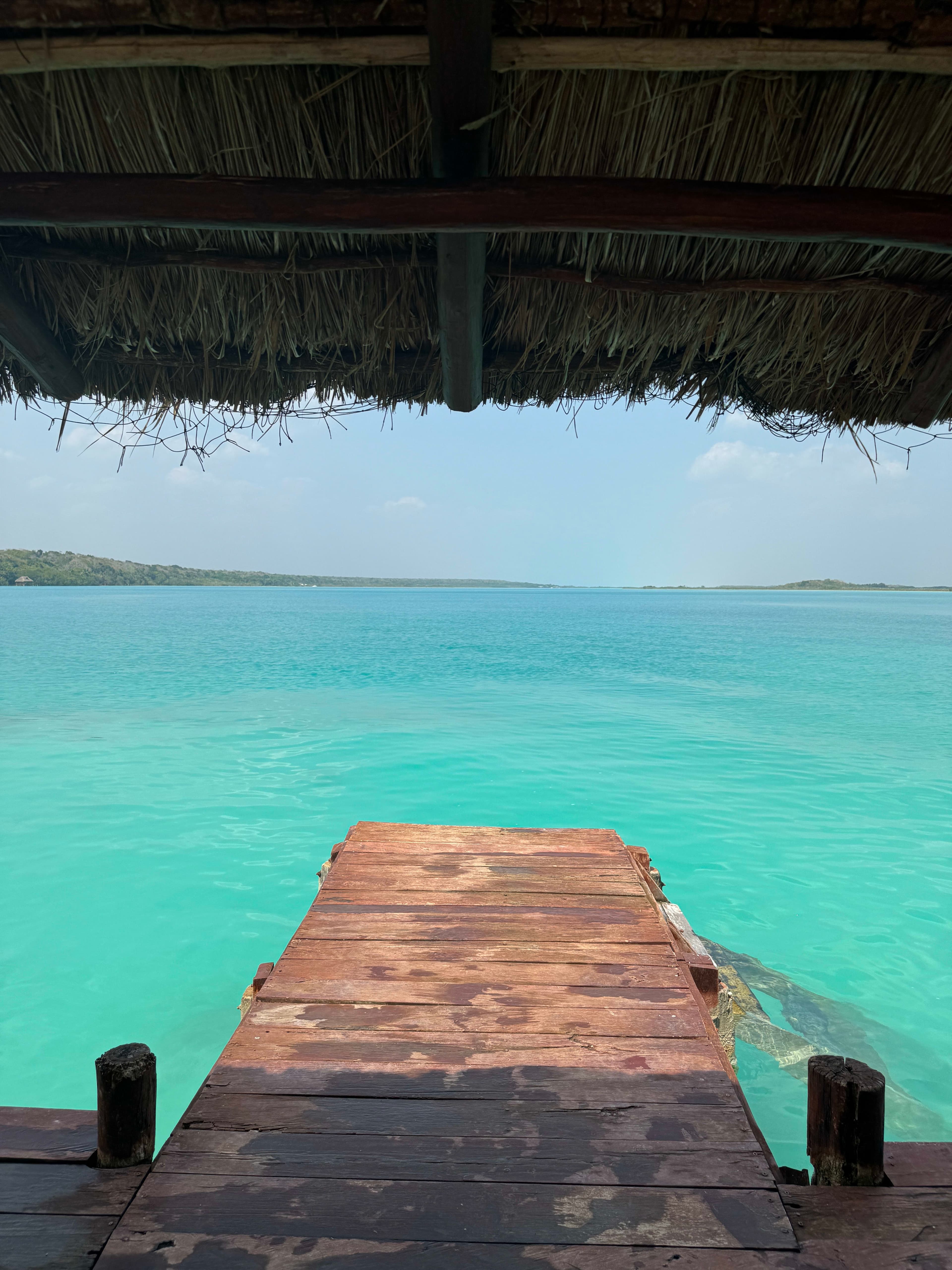 View of the end of a wooden dock stretching out to a bright turquoise ocean 