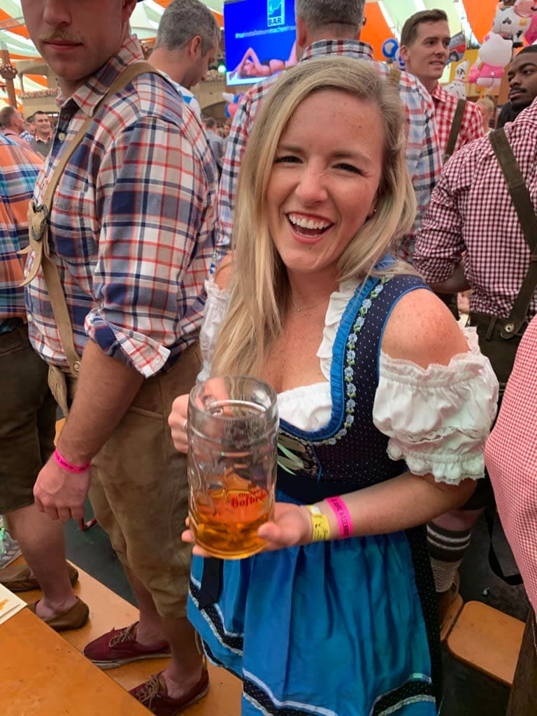 Picture of Olivia smiling at Munich Oktoberfest wearing traditional Bavarian clothes and holding a stein of beer