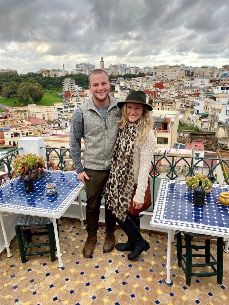 olivia and a friend posing on a rooftop with a beautiful city view in the background on a cloudy day