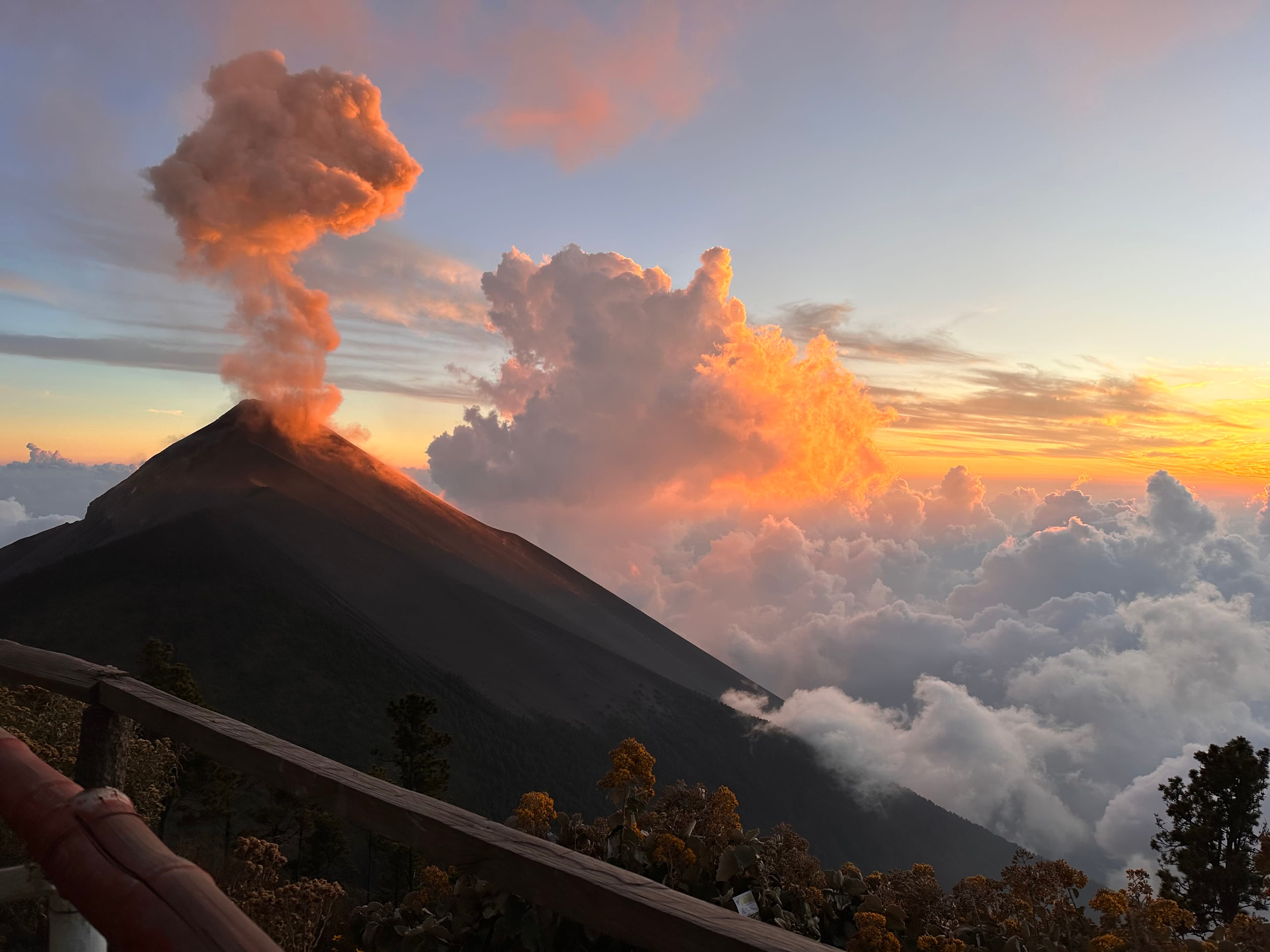 beautiful view of sunset above the clouds and an erupting volcan de fuego in Guatemala