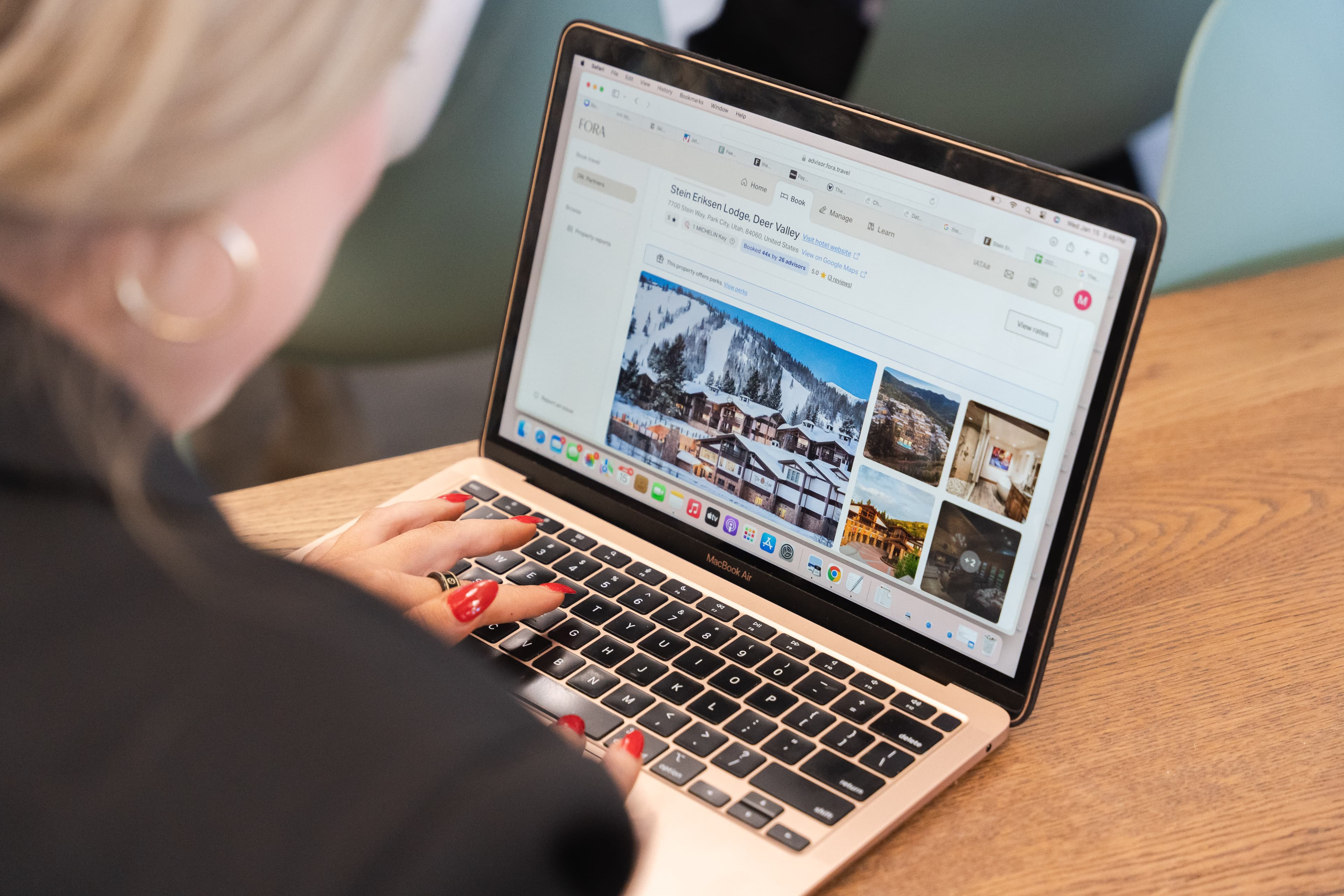 a woman in a gray sweater works on her laptop in a white room