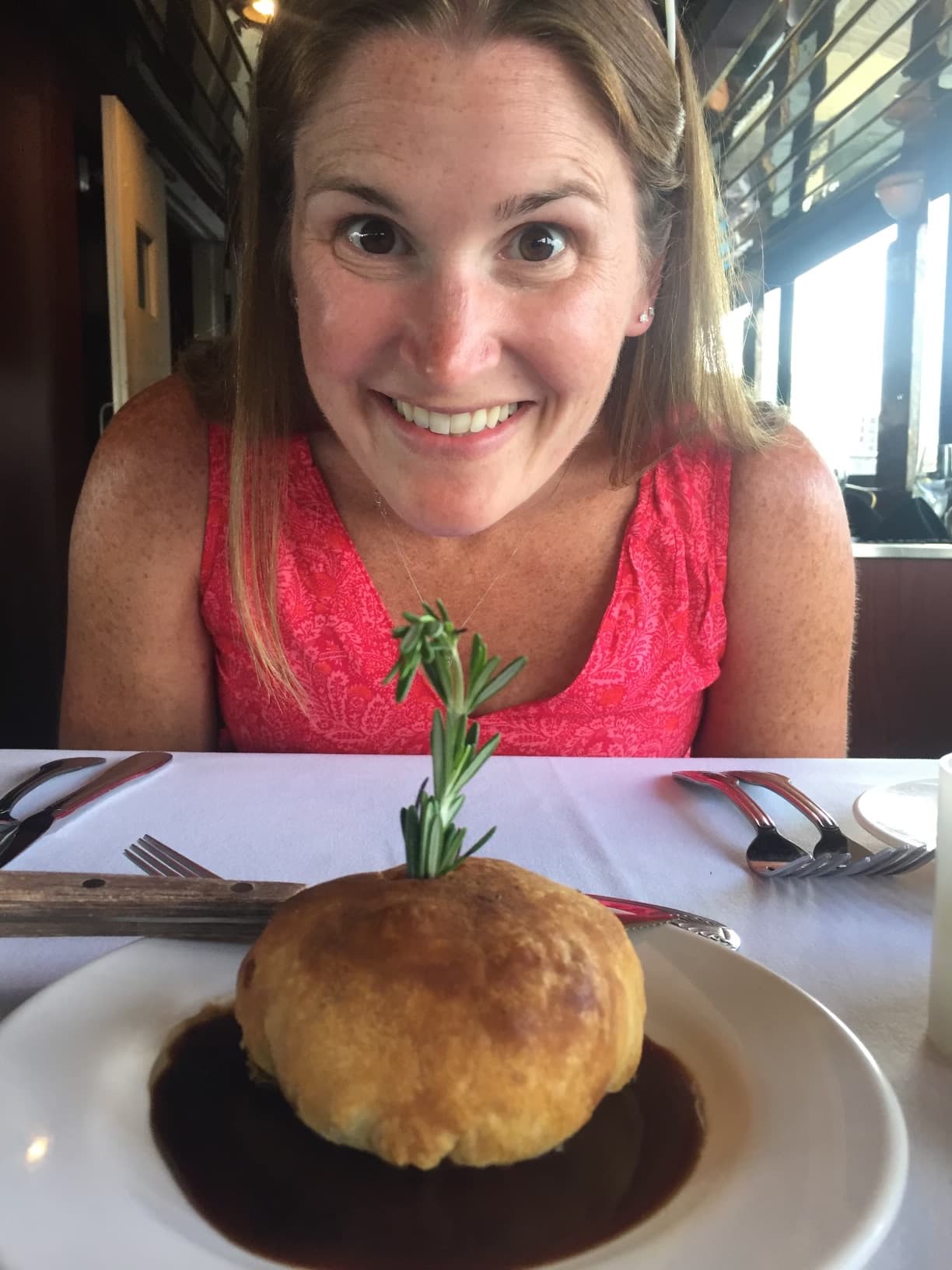 Travel advisor Erin posing with a a white place of food at a restaurant.
