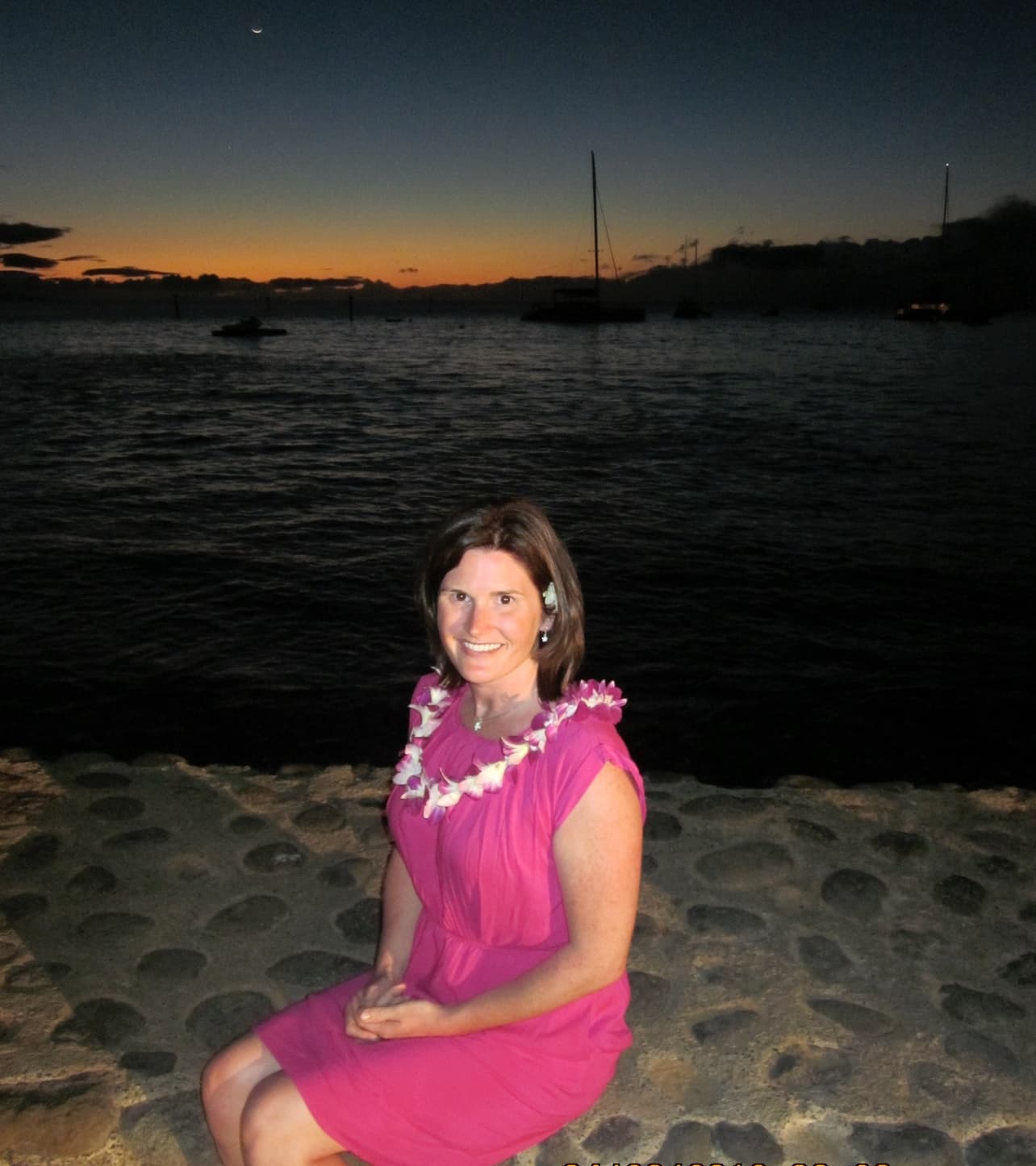 Travel advisor Erin sitting on a wall by the ocean at night