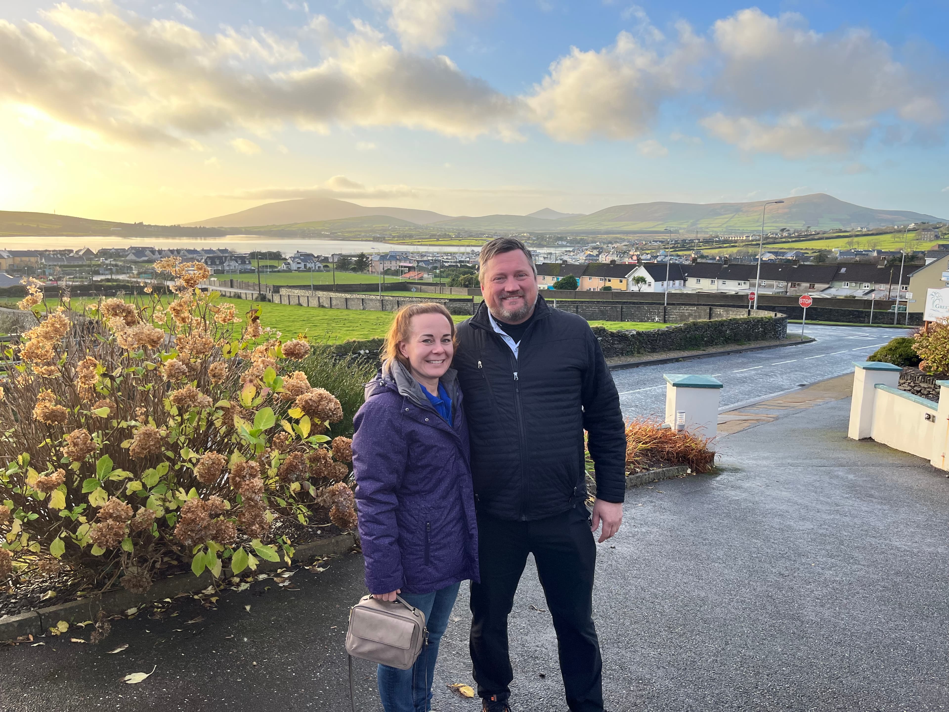 Picture of Amber and her partner smiling in front of a beautiful view at sunset in Dingle, Ireland