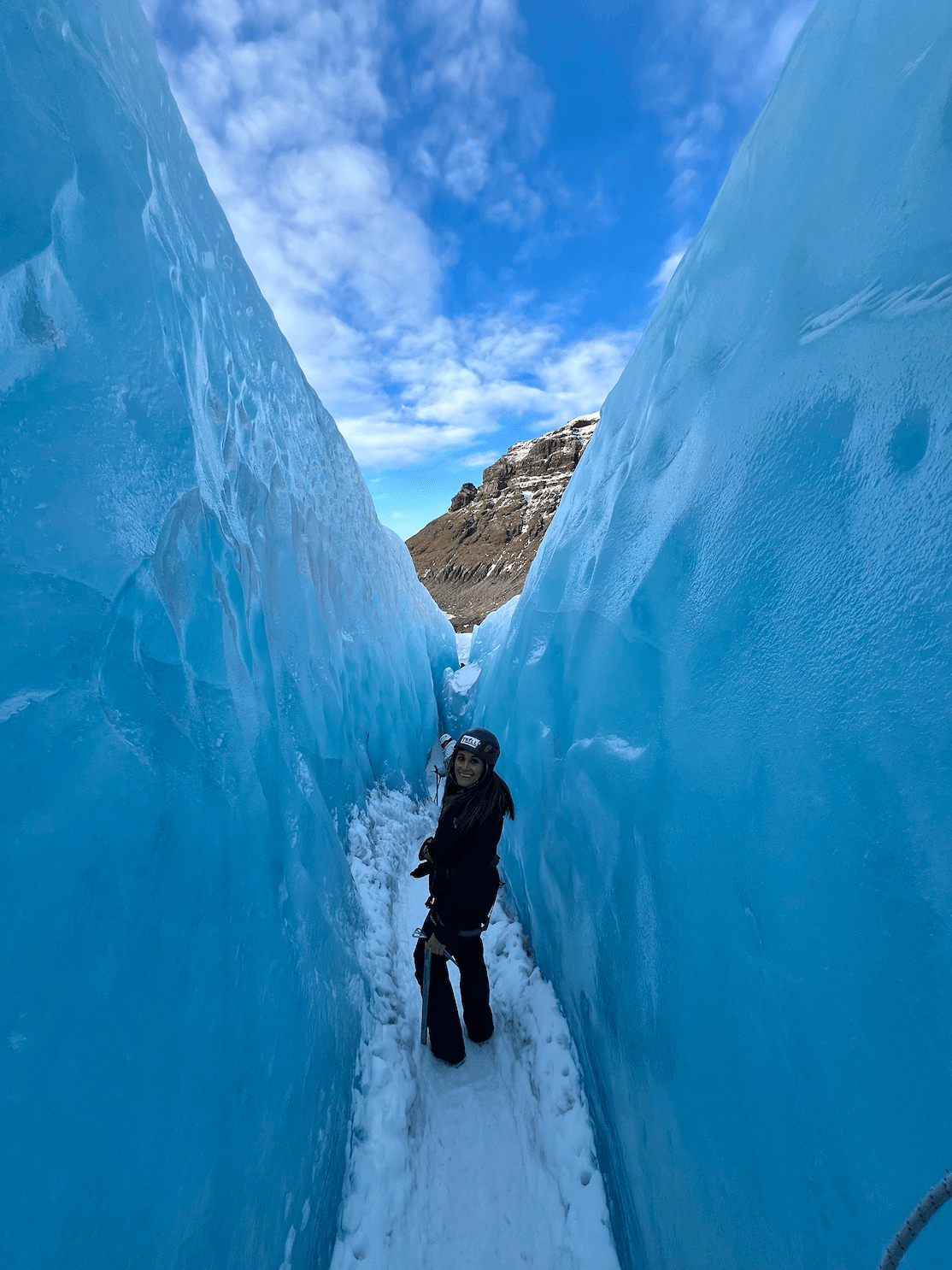 Photo of Sofia looking back at the camera from in between two large, blue glacier-like walls of ice
