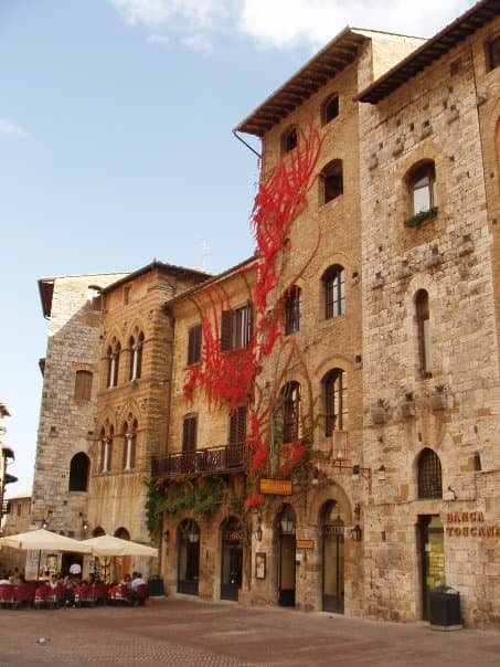 A sand colored building with a red decoration on it during the day. 