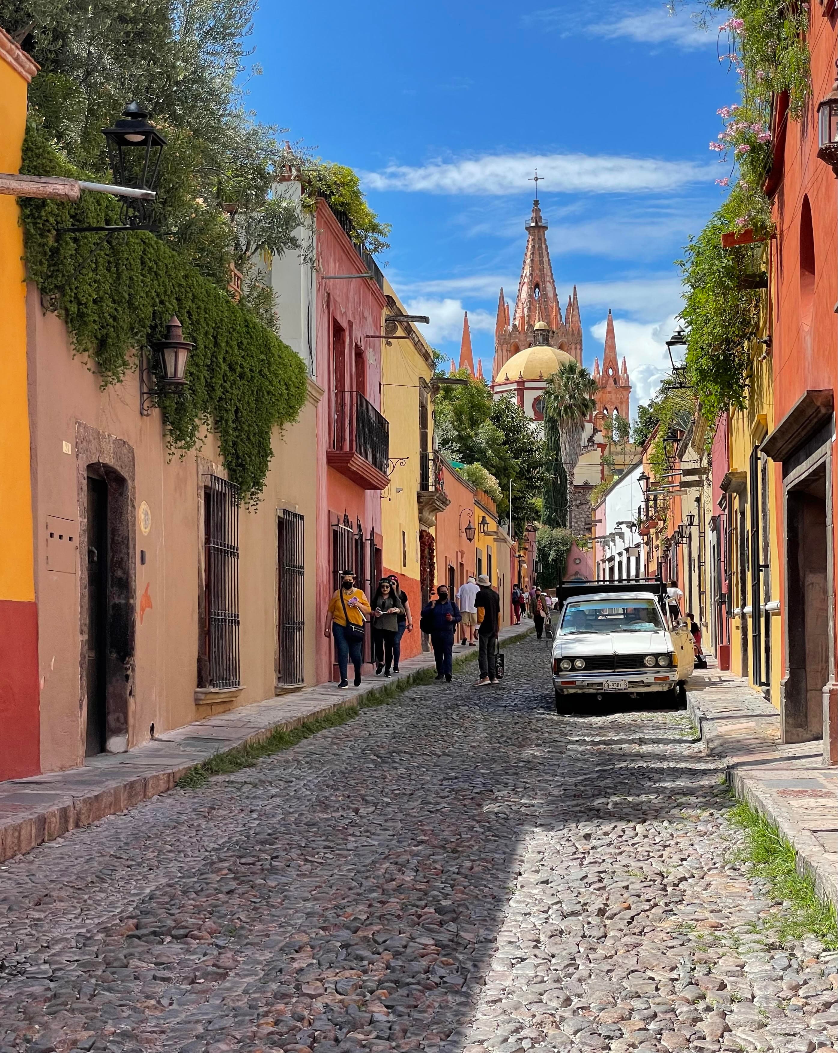 View of a stone street lined with pastel colored buildings in San Miguel de Allende, Mexico on a sunny day