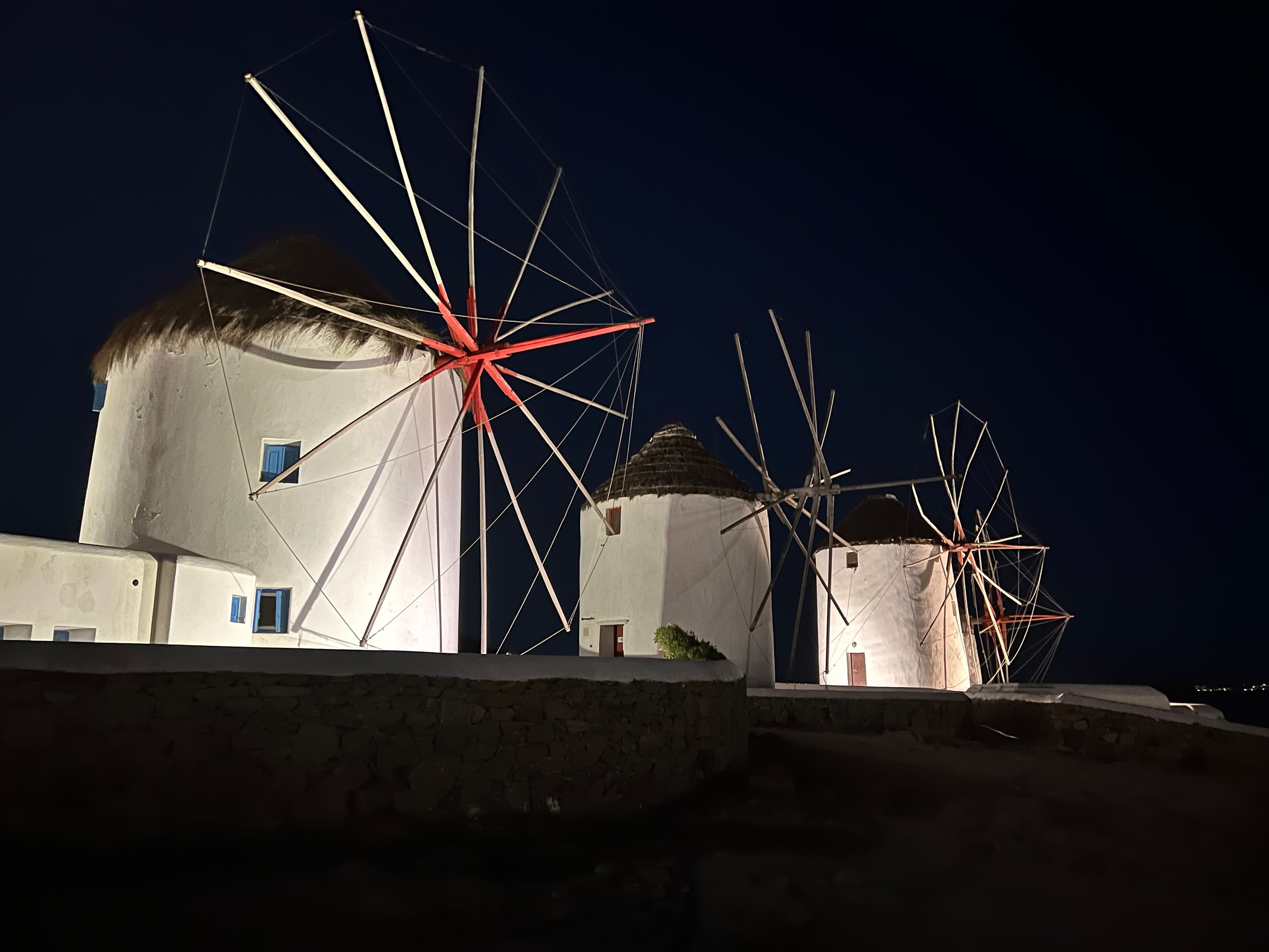 View of three white cylindrical windmills lit up at night