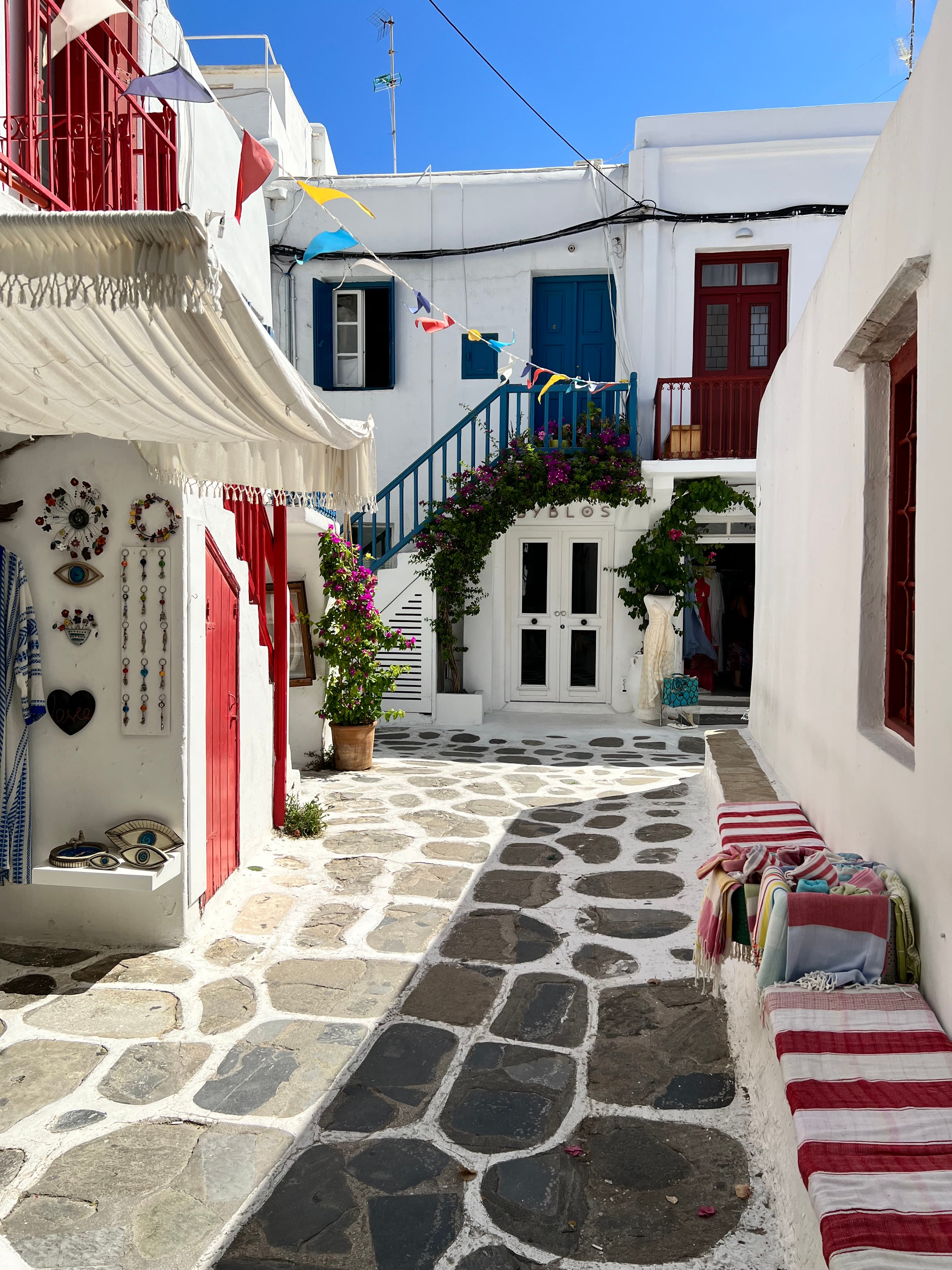Pretty view of a stone path between small white buildings with red doors on a sunny day