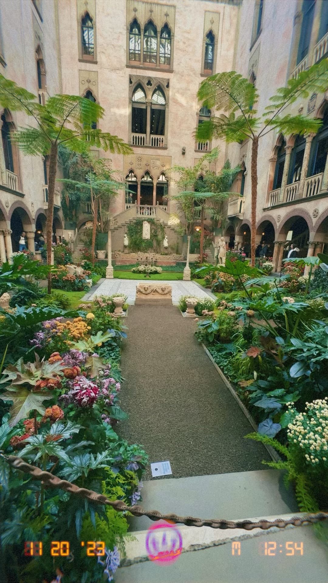 A film photo of a courtyard of a hotel with palm trees and other greenery lining the pathways within it. 