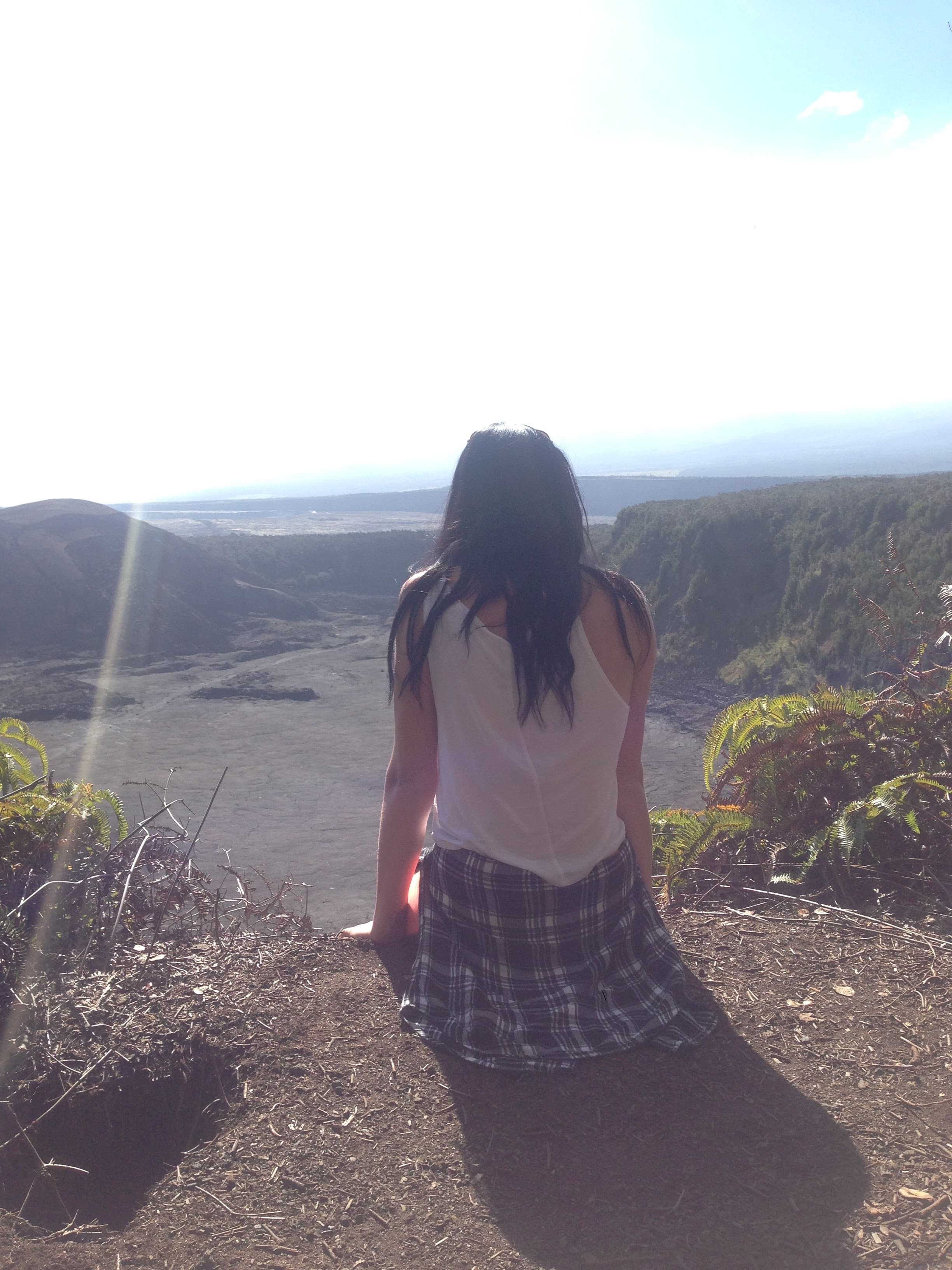  Nicole sitting on a ledge looking out over a valley landscape on a sunny day