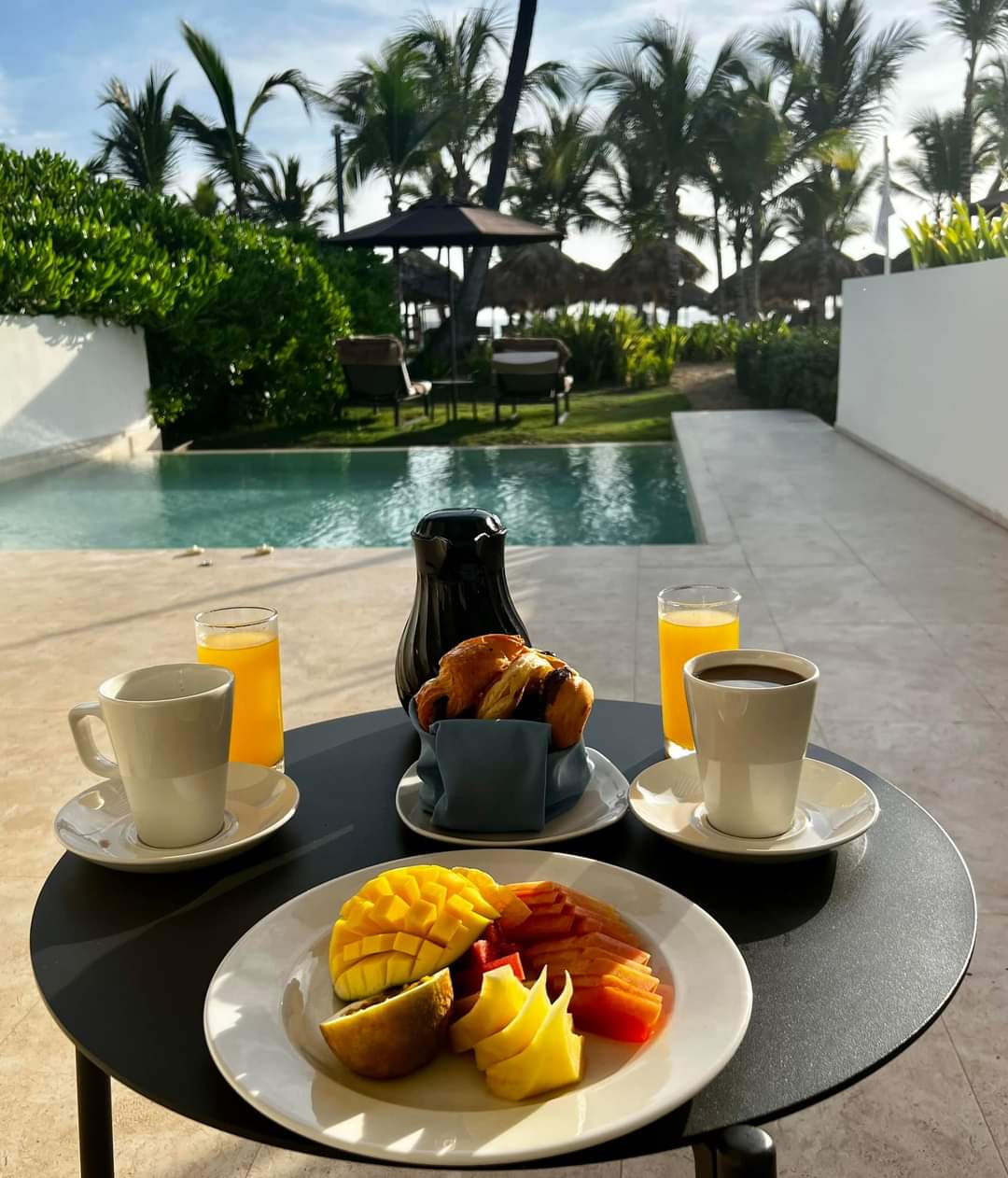 Breakfast in the morning near a private pool and palm trees in the distance.