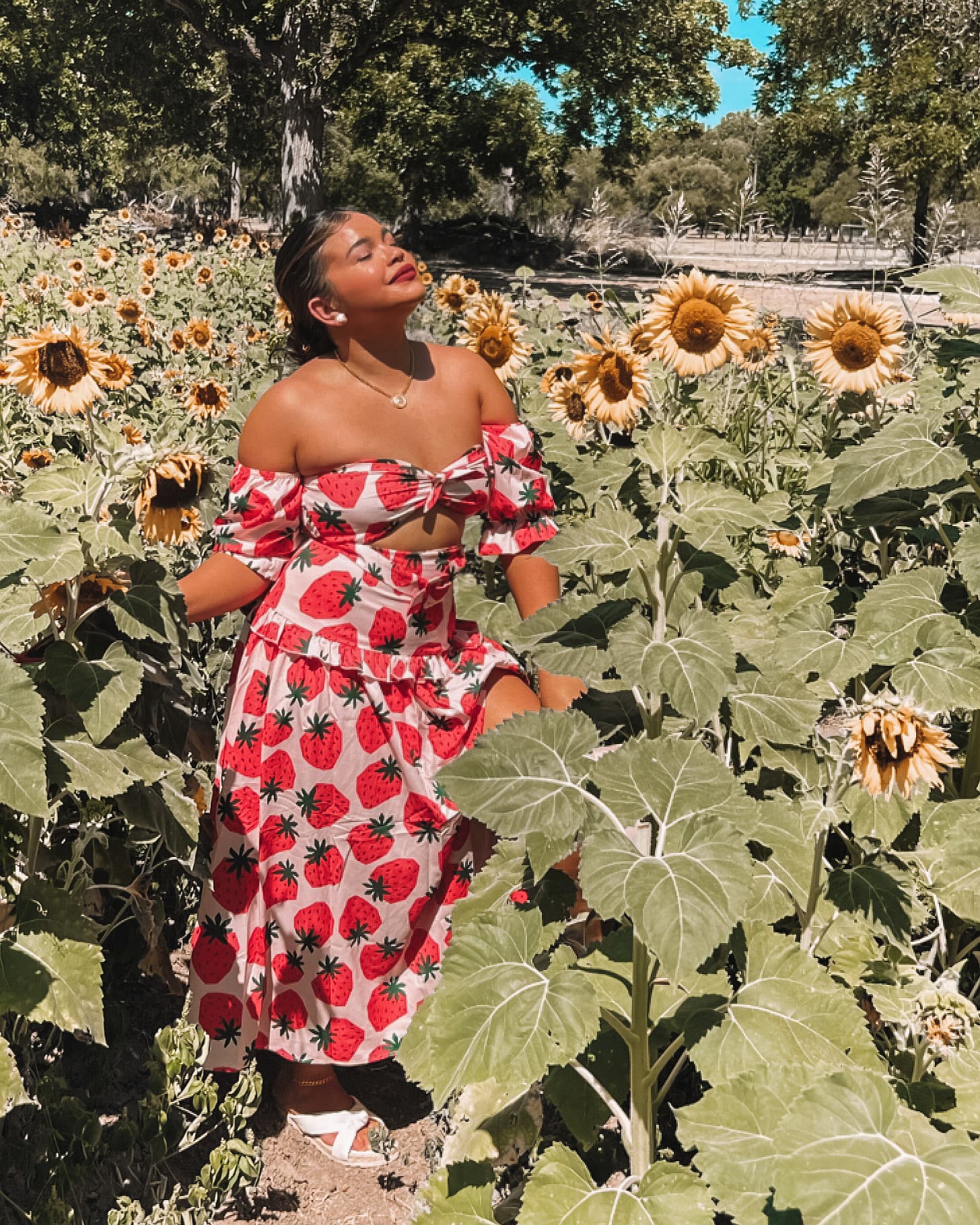Advisor posing for an image in a field of sunflowers in a beautiful dress on a sunny day. 