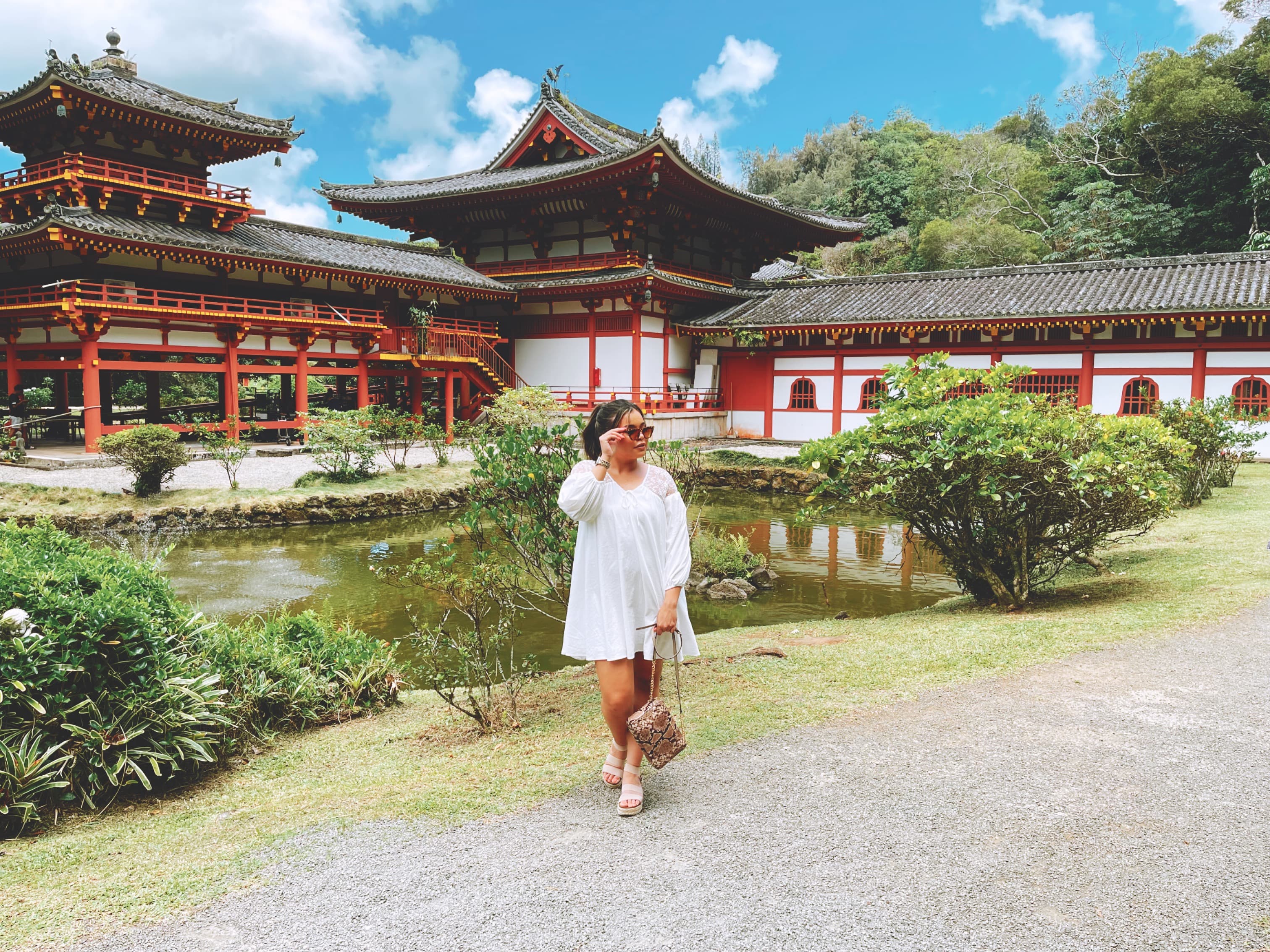 Advisor posing for an image in a white dress with a temple in the background on a sunny day. 