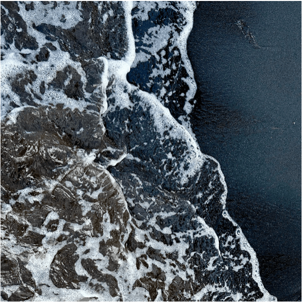 A close up image of a beach shoreline with ocean water brushing the sand. 